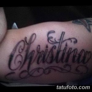 Фото тату надписи 'Christina' на плече. Черно-серая татуировка, выполненная в каллиграфическом стиле с декоративными элементами, выглядит эффектно и привлекательно.