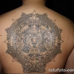 Фото тату: Большая татуировка календаря майя, покрывающая всю спину. Детализированный черно-серый рисунок с акцентом на центральное изображение бога солнца.