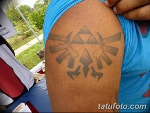 Фото тату символа Хайлиан из игры The Legend of Zelda на руке. Простой и стильный рисунок в серо-голубых тонах.