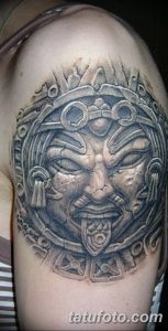 Фото тату: крупный рисунок календаря ацтеков на плече, выполненный в технике blackwork с высокой детализацией и реалистичными тенями.