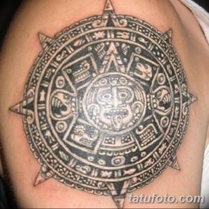 Фото тату на плече: изображение календаря ацтеков, выполненное в технике blackwork с четкими линиями и геометрическими узорами.