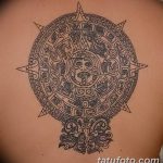 Фото тату на спине: изображение календаря ацтеков, выполненное в технике blackwork с четкими линиями и геометрическими узорами.