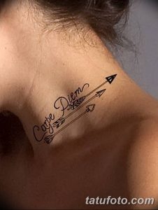 Фото тату надписи 'Carpe Diem' на спине, выполненной вместе с изображением стрелы. Черная татуировка с четкими линиями и минималистичным дизайном.