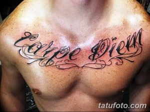 Фото тату надписи 'Carpe Diem' на груди мужчины. Черная каллиграфическая надпись с декоративными элементами, выполненная в классическом стиле.