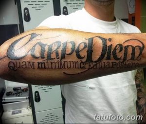 Фото татуировки 'Carpe Diem quam minimum credula postero' на предплечье. Черно-белый рисунок с крупными буквами и детальной проработкой.