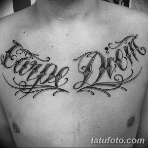 Фото татуировки 'Carpe Diem' на груди, выполненной каллиграфическим шрифтом. Черно-белый рисунок с изящными завитушками и детальной проработкой.