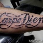 Фотография татуировки 'Carpe Diem' на предплечье. Черный контурный рисунок с декоративными элементами, выполненный профессиональным мастером тату.