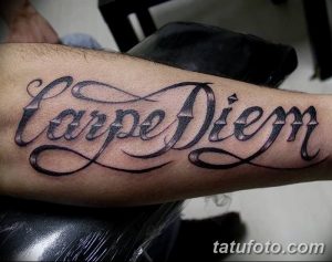 Фотография татуировки 'Carpe Diem' на предплечье. Черный контурный рисунок с декоративными элементами, выполненный профессиональным мастером тату.