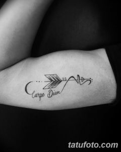 Фото тату 'Carpe Diem' с изображением стрелы и сердцебиения, символизирующих течение времени и жизнь. Расположена на руке, выполнена в черном цвете.