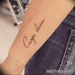Фото тату с надписью 'Carpe Diem' на внутренней стороне предплечья, выполненной тонкой линией. Простой и элегантный дизайн для тех, кто ценит минимализм.