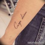 Фото тату: простая и элегантная надпись 'Carpe Diem' на руке, выполненная тонкой линией. Минималистичный стиль.