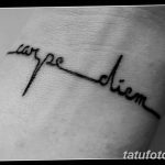 Фото минималистичной татуировки 'Carpe Diem' на запястье, выполненной тонкими черными линиями. Изящный рисунок татуировки.