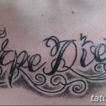 Фото тату надписи 'Carpe Diem' с витиеватыми узорами и завитушками, выполненной черными чернилами. Красивый и оригинальный дизайн.