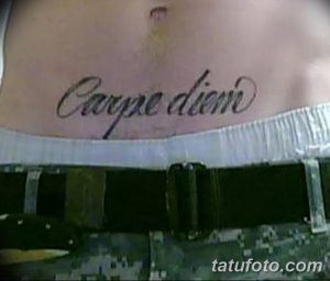 Фото тату надписи 'Carpe Diem' на пояснице, выполненной черными чернилами. Элегантный и привлекательный рисунок.
