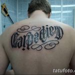 Фото татуировки надписи 'Carpe Diem', выполненной с декоративными завитушками на спине. Черно-белая татуировка.