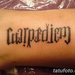 Фото татуировки надписи 'Carpe Diem', выполненной готическим шрифтом на руке. Черно-белая татуировка.