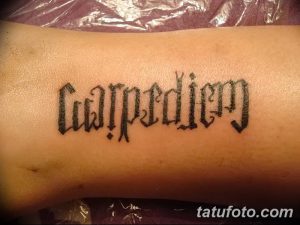 Фото татуировки надписи 'Carpe Diem', выполненной готическим шрифтом на руке. Черно-белая татуировка.