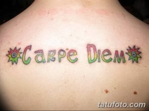 Фото тату надписи 'Carpe Diem' в ярких цветах с изображением цветов на спине. Оригинальный дизайн и красочная татуировка.