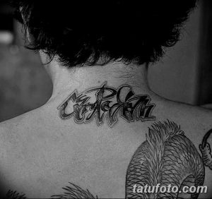 Фото тату надписи 'Carpe Diem' на затылке, выполненной в современном стиле. Черно-серая татуировка с динамичными линиями и необычным расположением.