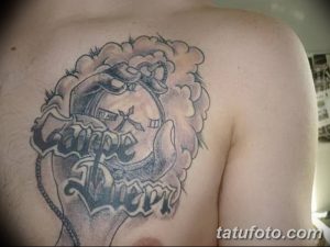 Фото тату 'Carpe Diem' с изображением корабля и морских элементов на груди. Черно-серый рисунок, детализированный дизайн. Подходит для любителей моря и приключений.