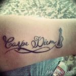Фото тату надписи 'Carpe Diem' с изображением скрипичного ключа. Черно-серый рисунок, выполненный на руке. Подходит для музыкантов и ценителей музыки.