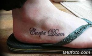 Фото тату надписи 'Carpe Diem' на стопе. Черный контур, простой шрифт, минималистичный дизайн. Идеально для любителей лаконичных татуировок.