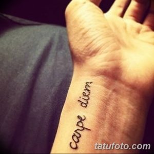 Фото тату с надписью 'Carpe Diem' на верхней части стопы, выполненной простым шрифтом. Минималистичный рисунок татуировки.