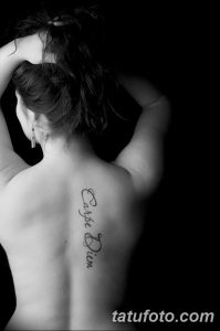 Фото тату с надписью 'Carpe Diem' на женской спине, выполненной изящным шрифтом. Минималистичный рисунок татуировки для вдохновения.