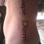 Фото татуировки надписи 'Carpe Diem', выполненной вдоль ребер. Элегантный и стильный рисунок тату для женщин.