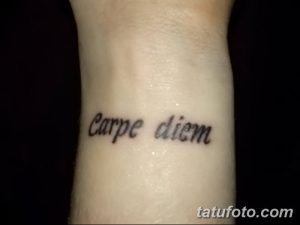 Фото простой татуировки надписи 'Carpe Diem' на запястье, выполненной черным цветом. Лаконичный и стильный эскиз тату для тех, кто ценит минимализм.