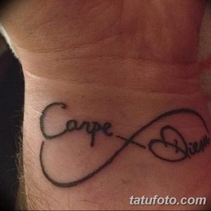 Фото тату надписи "Carpe Diem", вписанной в символ бесконечности на запястье. Черно-серый рисунок татуировки, выполненный простым шрифтом.