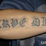 Фото тату надписи "Carpe Diem" на предплечье мужчины. Черно-серый рисунок татуировки, выполненный в готическом стиле.