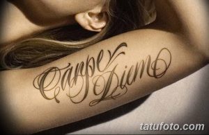 Фото тату надписи "Carpe Diem" выполненной каллиграфическим шрифтом на внутренней стороне предплечья женщины. Черно-серый рисунок татуировки.