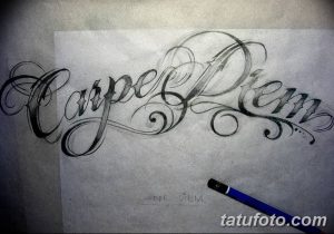 Фотография эскиза татуировки с надписью 'Carpe Diem', выполненного карандашом. Каллиграфический шрифт, детализированная проработка, реалистичный стиль.
