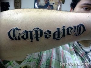 Фото готической татуировки с надписью 'Carpe Diem' на руке. Черно-белый рисунок татуировки с использованием готических шрифтов.
