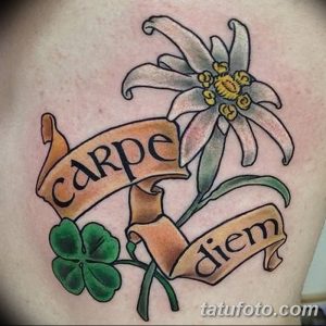 Фото цветной татуировки с надписью 'Carpe Diem', цветком эдельвейса и клевером. Яркий рисунок татуировки с использованием пастельных тонов.