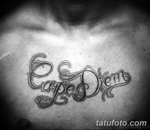Фото татуировки с надписью 'Carpe Diem' на груди. Черно-белый рисунок татуировки, выполненный в каллиграфическом стиле.