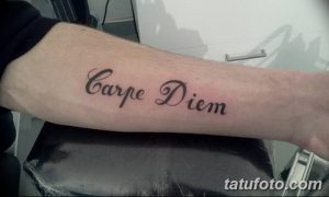 Фото тату с надписью 'Carpe Diem' на предплечье, выполненной классическим шрифтом. Простой и элегантный эскиз тату для ценителей минимализма.