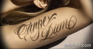 Фото тату с надписью 'Carpe Diem' на плече, выполненной в витиеватом стиле с использованием теней. Яркий эскиз тату для тех, кто любит выразительность.