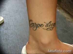 Фото тату с надписью 'Carpe Diem' на лодыжке, выполненной изящным шрифтом с завитушками. Красивый эскиз тату для девушек.