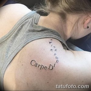 Фото татуировки 'Carpe Diem' с изображением летящих птиц на спине. Черно-белая татуировка, минималистичный стиль, символизм свободы.