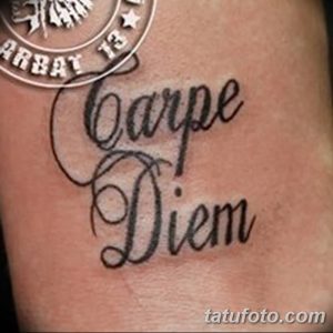 Фото татуировки 'Carpe Diem' с изображением герба и элементов милитари на руке. Черно-белая татуировка, реалистичный стиль, брутальный дизайн.