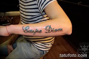 Фото тату: надпись 'Carpe Diem' яркими цветами на предплечье. Оригинальный рисунок татуировки, выполненный в стиле леттеринг.