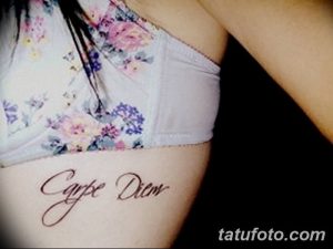 Фото тату: надпись 'Carpe Diem' красивым шрифтом на боку девушки. Нежный рисунок татуировки, выполненный в пастельных тонах.