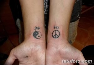 Фото тату на запястьях: с одной стороны символ мира и иероглиф, с другой - инь-ян и иероглиф, выполненные в черном цвете.