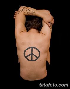Фото тату: простой черный символ мира на спине мужчины, с точечным узором на плече.