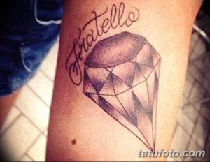 Фото тату бриллианта с надписью 'Fratello' на предплечье. Черно-серый рисунок татуировки, выполненный в реалистичном стиле, символизирует ценность братской любви.