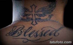 Фото тату с надписью 'Blessed' на шее, выполненное в черном цвете с добавлением тонких линий и градиентов. Крест с крыльями.