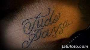 Фото тату на руке: надпись "Tudo Passa" выполненная в черном цвете, с красивым, витиеватым шрифтом. Минималистичный дизайн.