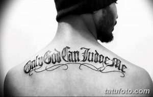 Фото тату надписи 'Only God Can Judge Me' готическим шрифтом на спине мужчины. Черно-белое изображение, детальная проработка букв.